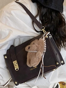 Minimalist dark brown leather square shoulder bag with gold hardware and plush charm