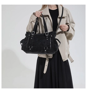 Detail of black multi-pocket tote bag with silver rivets and dual handle straps