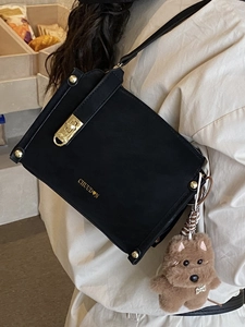 Minimalist black matte crossbody bag with gold hardware and a cute plush dog pendant