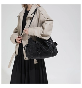 Detail view of large black matte leather tote bag featuring metal buckles and punk style