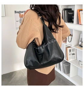 Gros plan sur un sac cabas en cuir noir avec œillets métalliques argentés à l'épaule