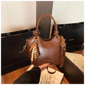 Détail du sac à main vintage marron avec pompon en perles de bois colorées et anneaux en métal