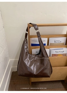 Détail du sac hobo marron brillant avec œillets argentés décoratifs et texture cuir lisse