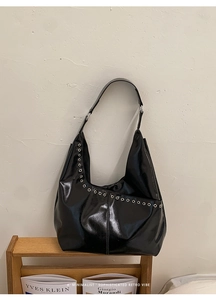 Détail du sac cabas noir brillant avec œillets métalliques argentés et design rétro minimaliste