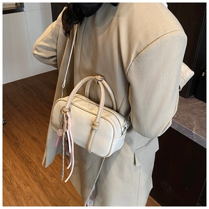 Détail du sac Boston beige montrant le cuir texturé, les glands tissés et la bandoulière