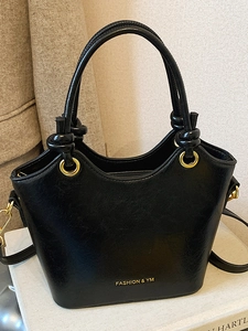 Sac à main élégant en cuir noir avec anneau doré et design à bords ondulés