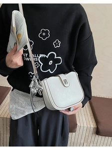 Detail of cream leather square crossbody bag with star pendant and silver hardware