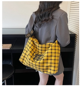Detail view of yellow plaid tote bag with heart embroidery and adjustable leather strap
