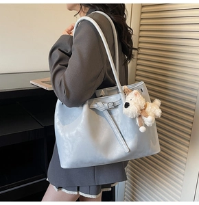 Détail d'un grand sac cabas bleu clair en similicuir avec boucle et pendentif chien en peluche