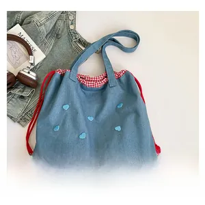 Detailaufnahme der blauen Canvas-Tasche mit Herzstickerei und rotem Kordelzug
