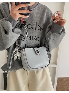 Dettaglio del ciondolo a stella d'argento su una borsa strutturata grigio-blu di tendenza