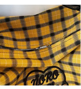 Detail of grid patterned tote bag featuring a smooth metal zipper and heart embroidery