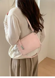 Detail view of light pink rectangular shoulder bag with silver turn-lock on female model