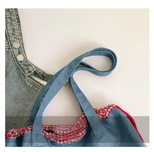Detail der Denim-Tragetasche mit verstärkten Griffen und rot-weiß kariertem Futter