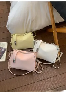 Detailed view of three pastel baguette bags with silver locks in yellow, cream, and pink