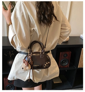 Detail of vintage coffee leather handbag with gold zipper and cute bear charm