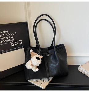 Détail d'un grand sac cabas noir en cuir avec boucle et breloque petit chien blanc