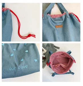 Detail der Denim-Tasche mit Herzbestickung, Lederetikett und rotem Karofutter