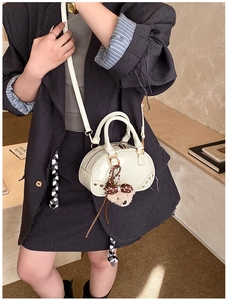 Detail of vintage-style off-white leather handbag with metal studs and cute bear pendant
