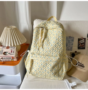 Detail of light yellow backpack showing textured bubble fabric and blue floral print