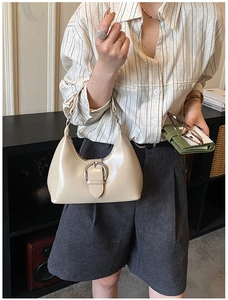 Détail du sac hobo beige en demi-lune avec boucle argentée dans un cadre urbain chic