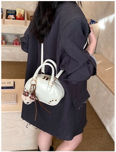 Close-up of white mini boston bag with metal studs and cute plush bear charm detail