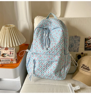 Detail of light blue floral bubble fabric backpack with woven rope zipper pulls