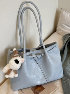 Grand sac cabas bleu clair en similicuir avec un charmant ours en peluche sur un lit blanc