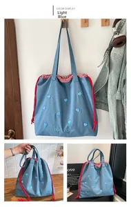 Detailansicht der hellblauen Denim-Tasche mit Herzstickerei und rotem Kordelzugverschluss