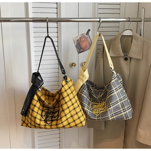 Detail view of plaid tote bags with 'NORO LIVE' heart embroidery and knotted straps