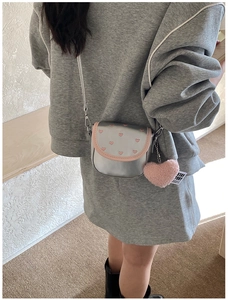 Détail d'un sac argenté avec broderie coeur rose et breloque en peluche douce