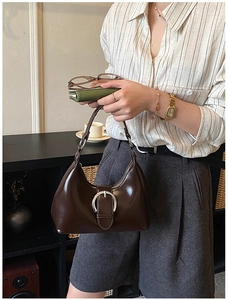 Gros plan sur un grand sac hobo marron foncé avec boucle fer à cheval argentée et fini brillant