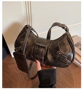 Macro shot of dark brown crinkled leather texture and retro bronze metal hardware on bag