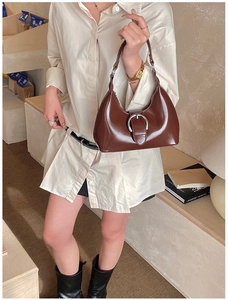 Détail d'un sac hobo marron foncé brillant avec une grande boucle en métal argenté ronde