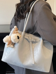 Sac fourre-tout bleu gris mat avec charm chien en peluche porté par un mannequin