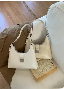 Detail view of white and beige baguette bags on sofa with metallic rectangular buckles