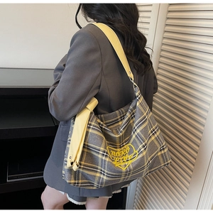 Detail of checkered tote bag with yellow heart embroidery and leather shoulder strap