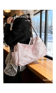 Detailed embroidery of unicorn and stars on a pink satin tote bag with brown straps