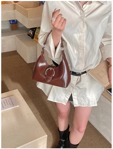 Détail du sac sous le bras en cuir marron foncé avec boucle métallique en fer à cheval