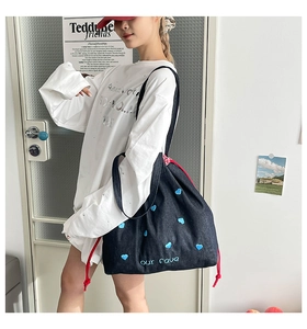 Detail der blauen Jeans-Tasche mit Herz-Stickerei, rotem Kordelzug und schwarzem Gurt