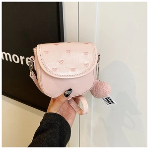 Détail d'un petit sac bandoulière rose carré avec broderie coeur et pompon en fourrure