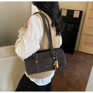 Close-up of charcoal gray shoulder bag with beaded charm and gold ZHCNMA brand logo