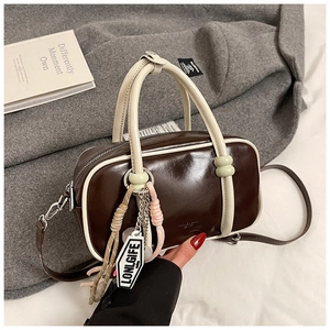 Gros plan d'un sac Boston marron avec des anses contrastées et des charms design