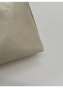 Close-up of premium beige leather bag showing soft lychee grain texture and matte finish
