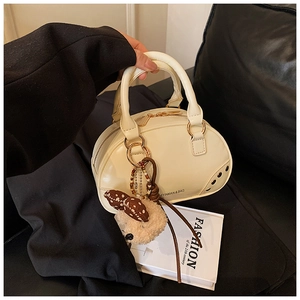 Detailed shot of cream-colored vintage handbag with gold hardware and plush bear charm