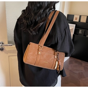 Detail showing vintage brown leather shoulder bag with beaded fringe and ZHCNMA logo
