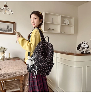 Detail of floral black quilted backpack with plush bunny charm and striped drawstring decor