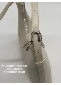 Detail view of the cream tote bag showing the adjustable shoulder strap and silver buckle