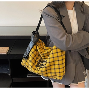 Detail of hobo shoulder bag featuring yellow plaid canvas and heart embroidery