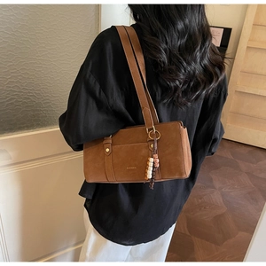 Detailed view of brown suede underarm bag with decorative beads and golden hardware